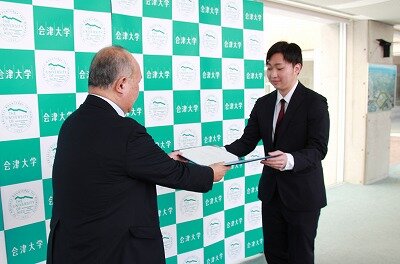 束原理事長兼学長から認定証を受け取る代表の山下